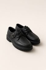CHÉDA · Soulier boucle tressé noir — vue de face, fond nacre