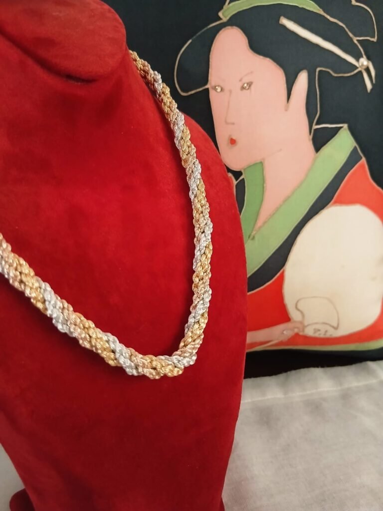 Collier torsadé doré et argenté porté sur buste rouge, Idrissi's brand